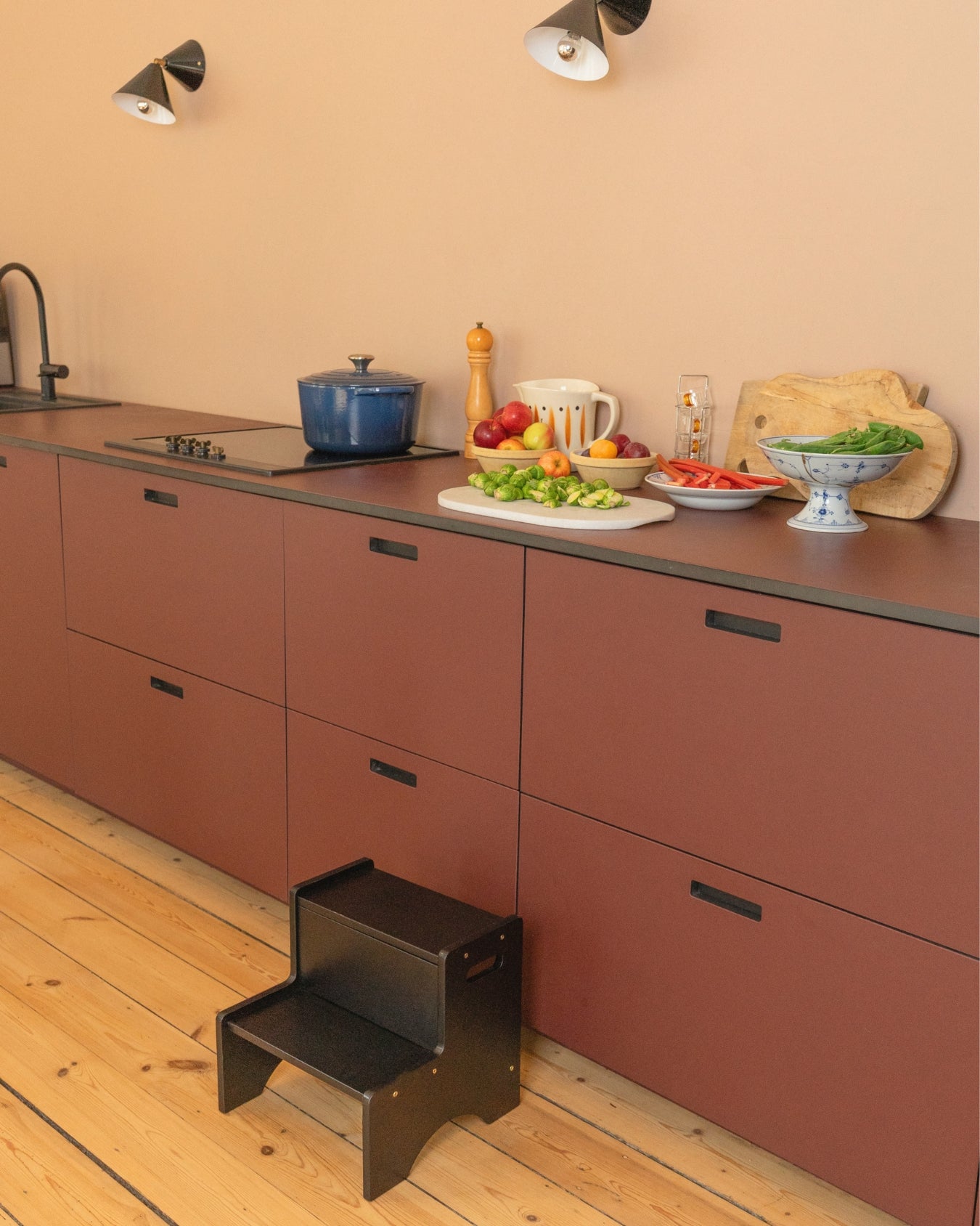 Kitchen with red cabinets, a step stool, and various kitchen items on the counter.