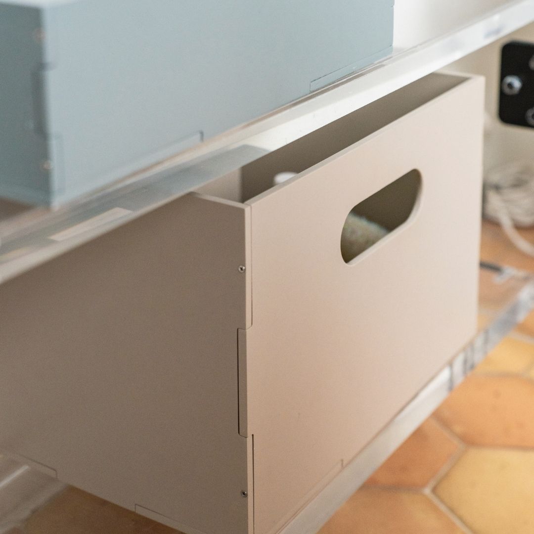 Close-up of a kitchen cabinet with a partially open door, showing a tiled floor.