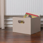 Beige storage box with colorful items on a wooden floor