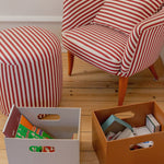 Red and white striped chair and ottoman with storage boxes on a wooden floor.