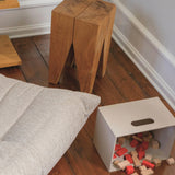 Wooden stools and a white box with colorful blocks on a wooden floor.