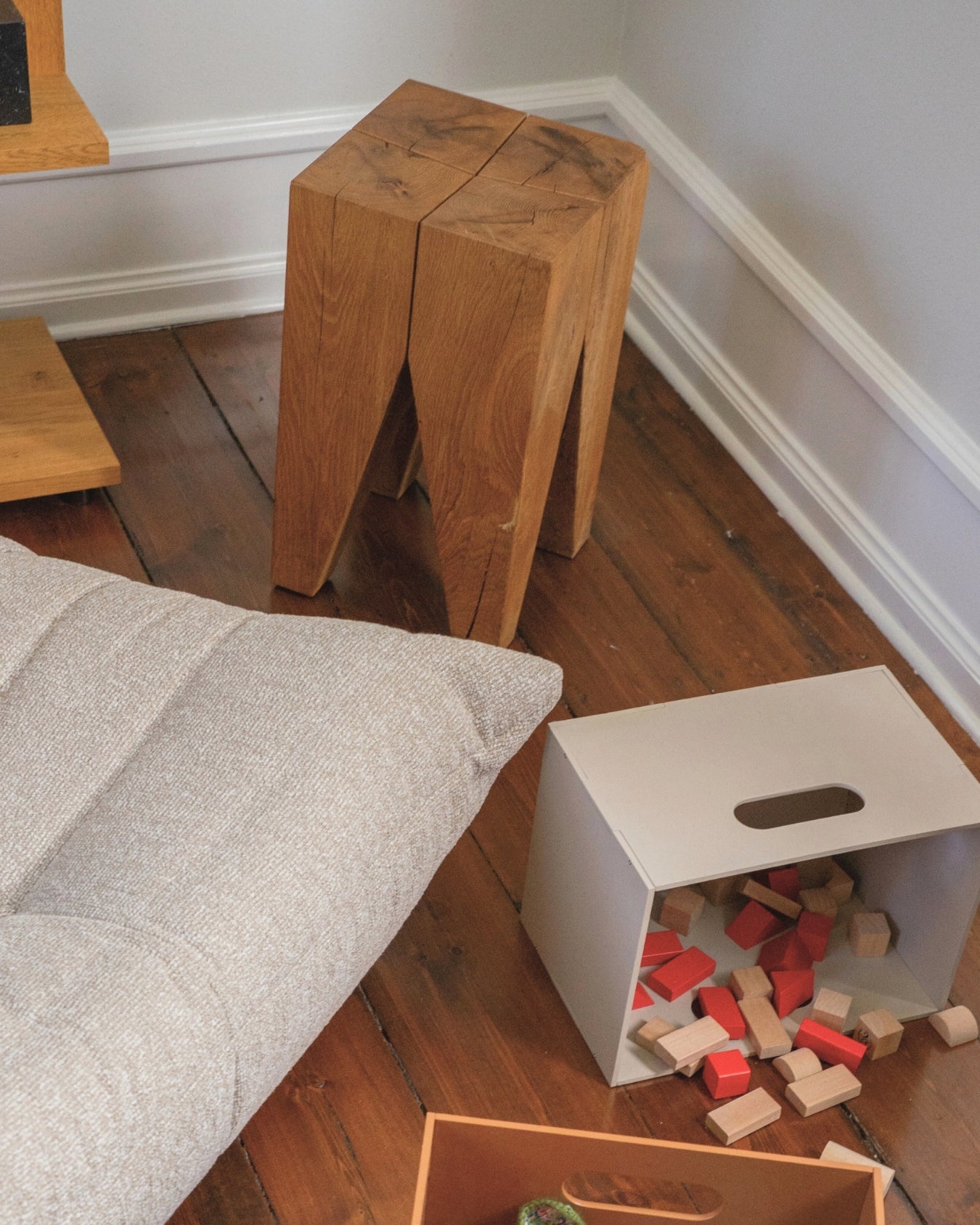 Wooden stools and a white box with colorful blocks on a wooden floor.