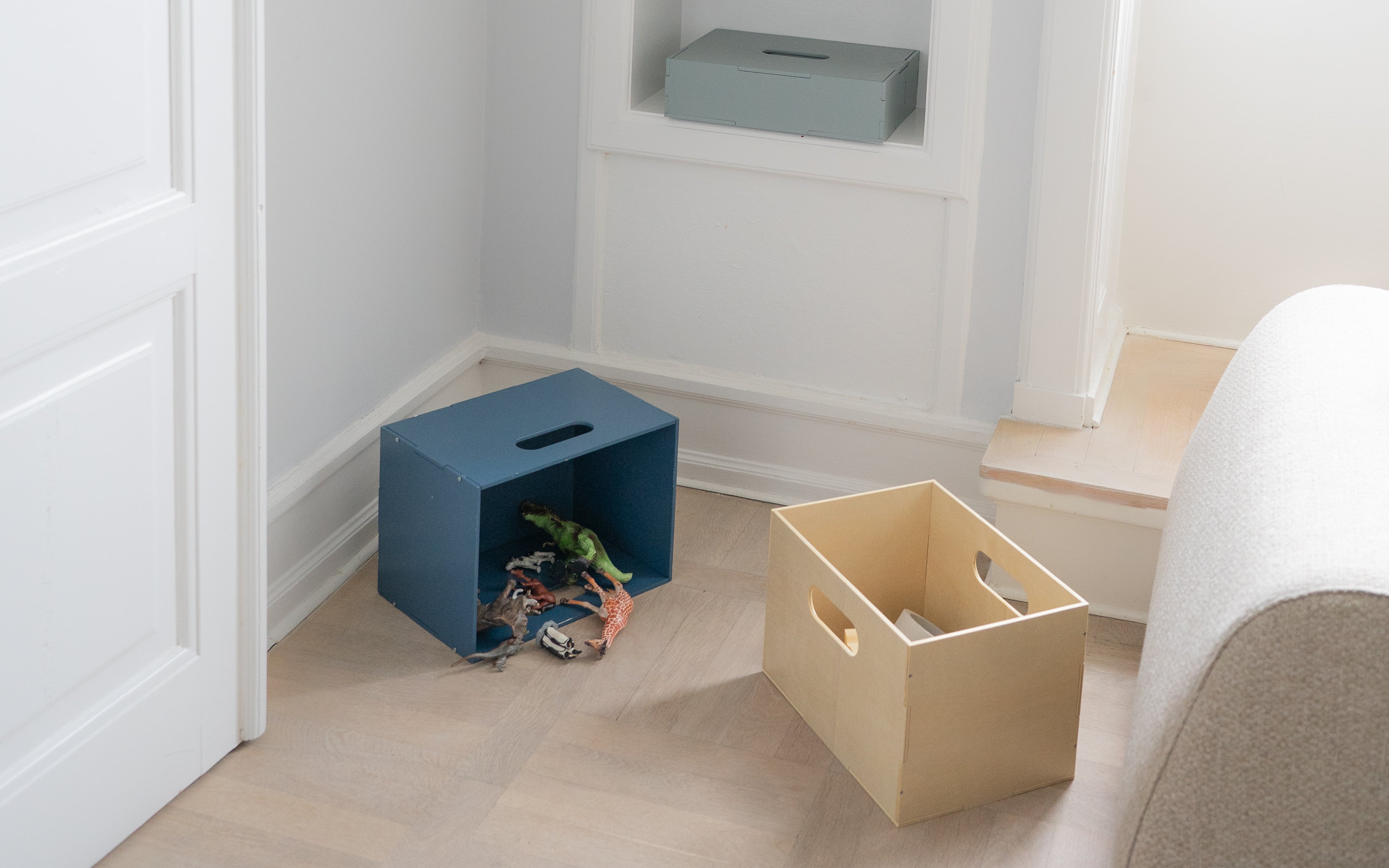 two storage boxes in the living room, one of which filled with toys
