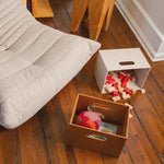 Children's toys in Kiddo boxes on a wooden floor with a sofa in the background