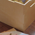 Wooden box on a wooden floor with a pen and paper in the foreground