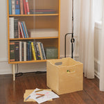 Wooden storage box on a wooden floor next to a bookshelf with books.