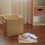 Wooden crate on a wooden floor with markers and paper on top