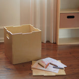 Wooden crate on a wooden floor with markers and paper on top