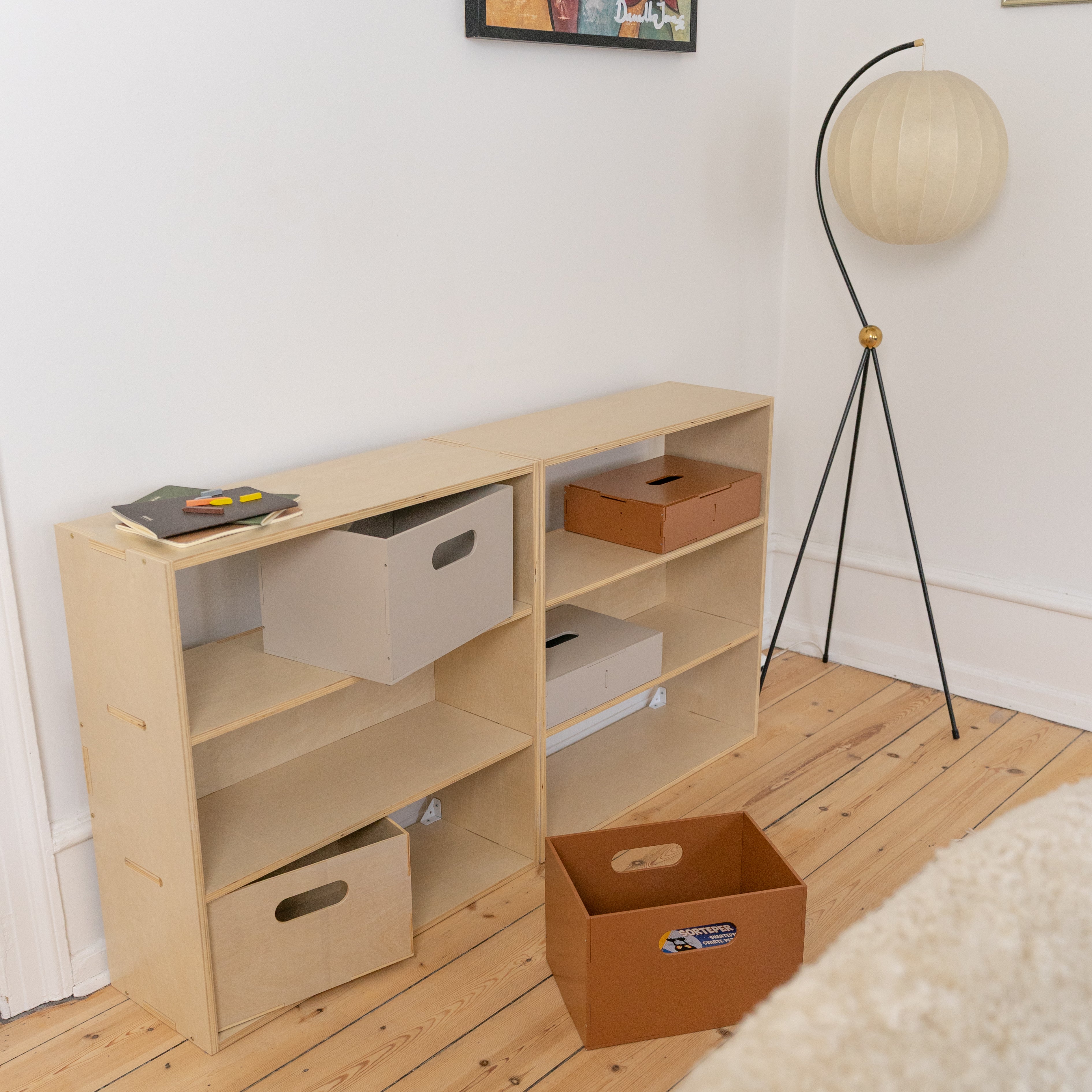 Wooden shelf with storage boxes in a room with a lamp and framed picture on the wall.