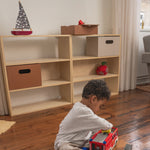 Child playing with a toy truck on a wooden floor in front of a bookshelf.