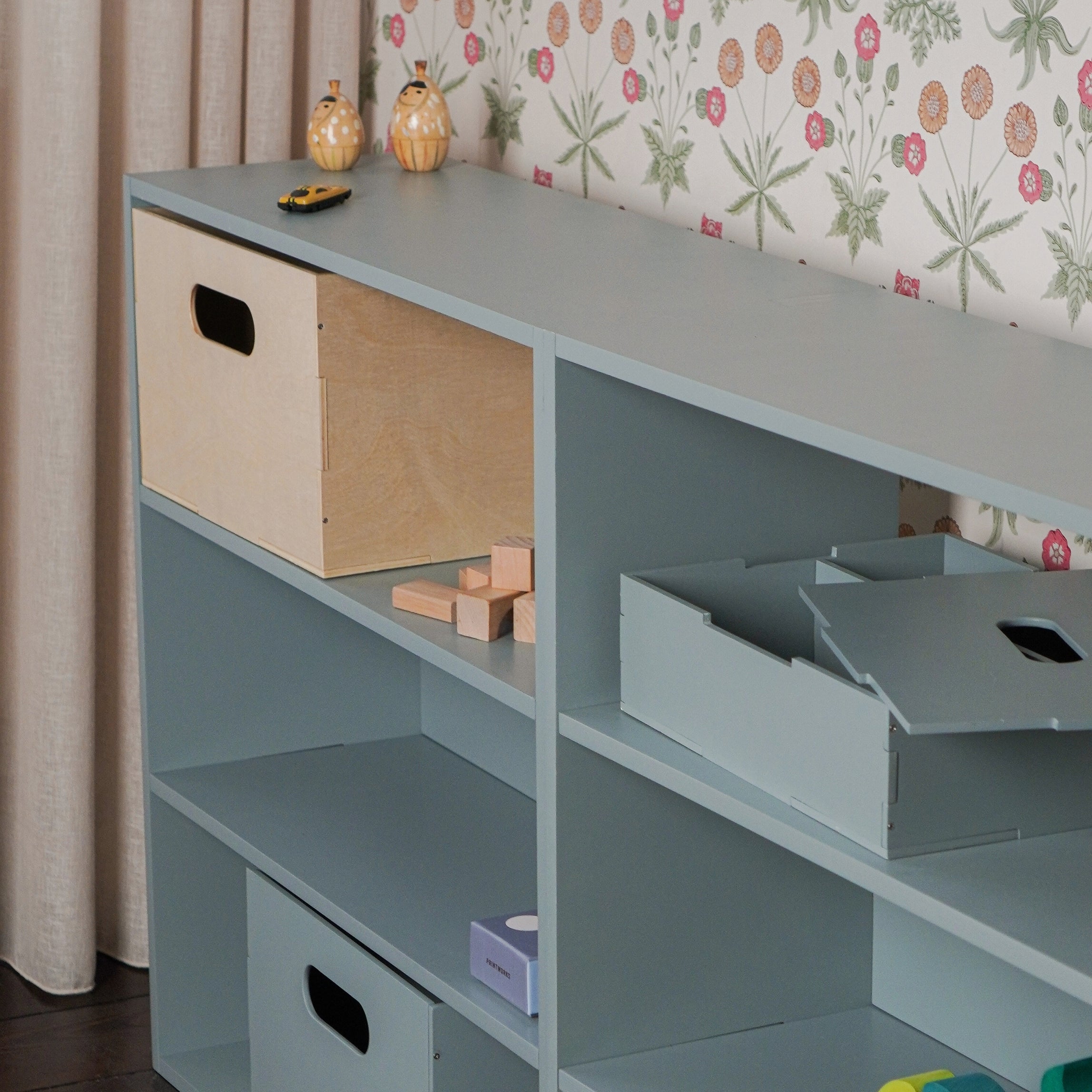 A shelving system in olive green with the boxes inside it