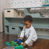 A shelving system in the kids room with a kid playing in front of it