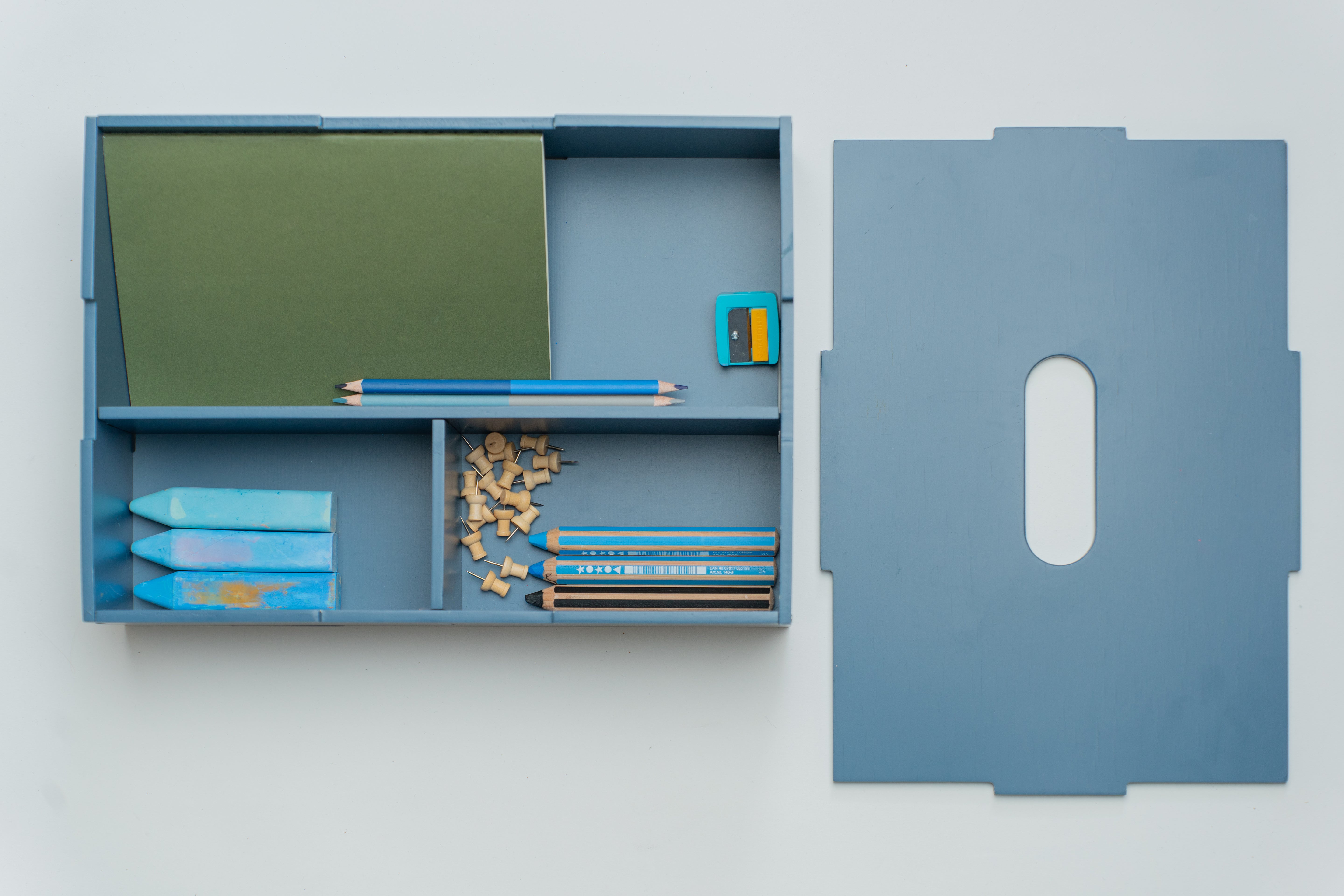 Blue pencil case with stationery items on a white background
