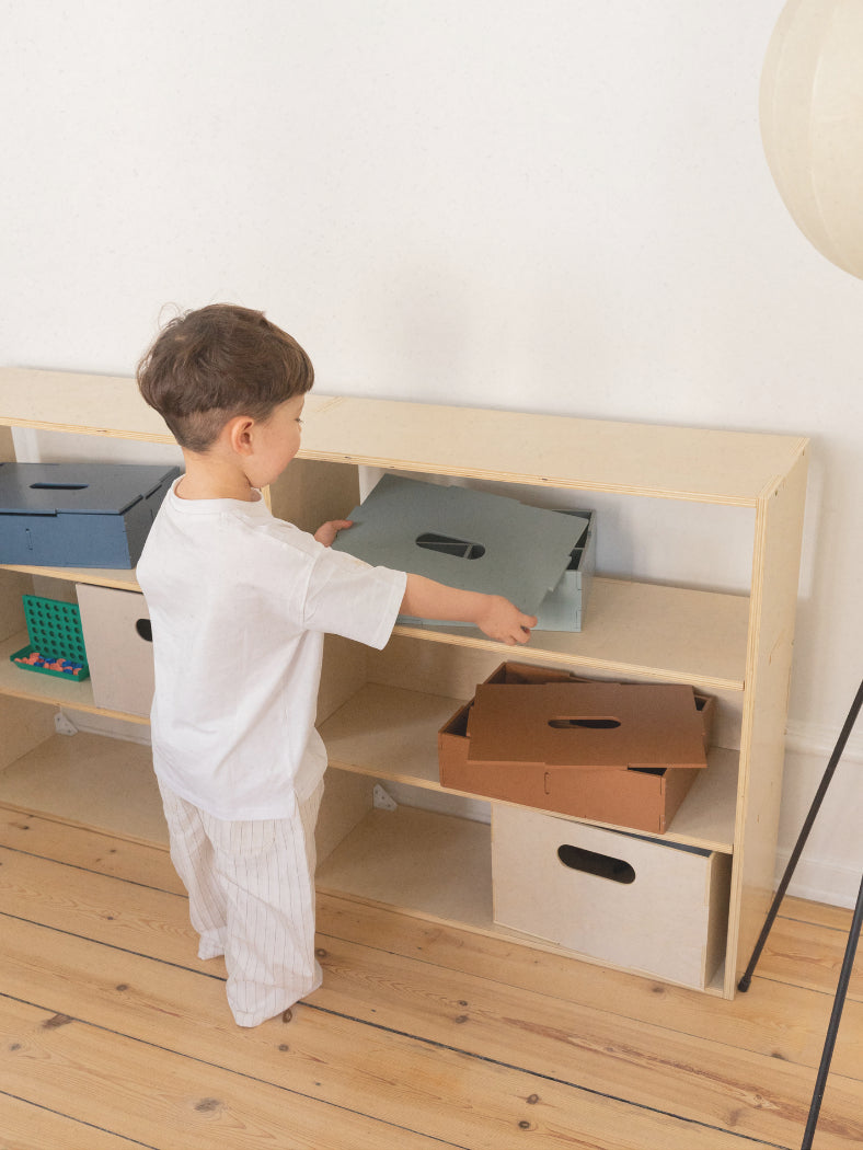 Child interacting with a wooden shelf in a minimalistic room