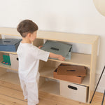 Child interacting with a wooden shelf in a minimalistic room