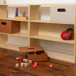 Wooden bookshelf with storage boxes and toys on a wooden floor.