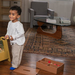 Child playing with toys on a wooden floor in a living room.