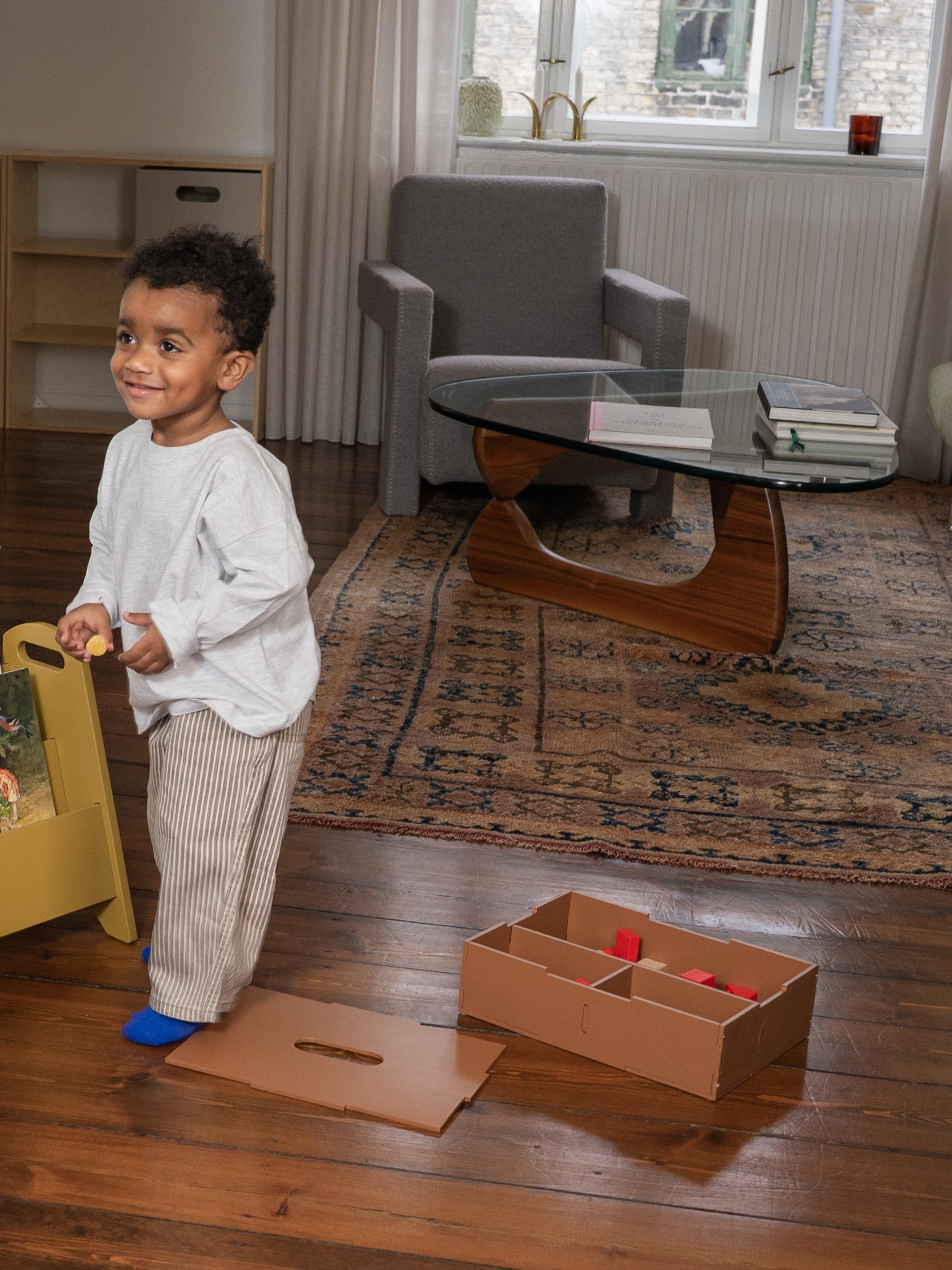 Child playing with toys on a wooden floor in a living room.