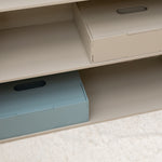 Beige shelves with two storage boxes, one open and one closed, on a light-colored floor.