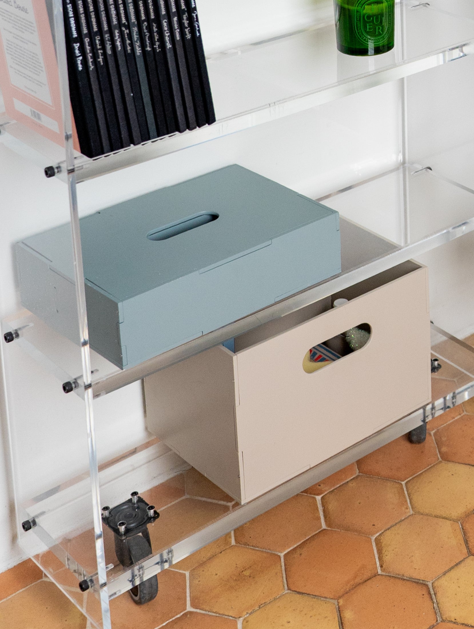 Storage boxes on a metal shelf with hexagonal tiles on the floor