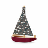 Model sailboat with a patterned sail on a white background