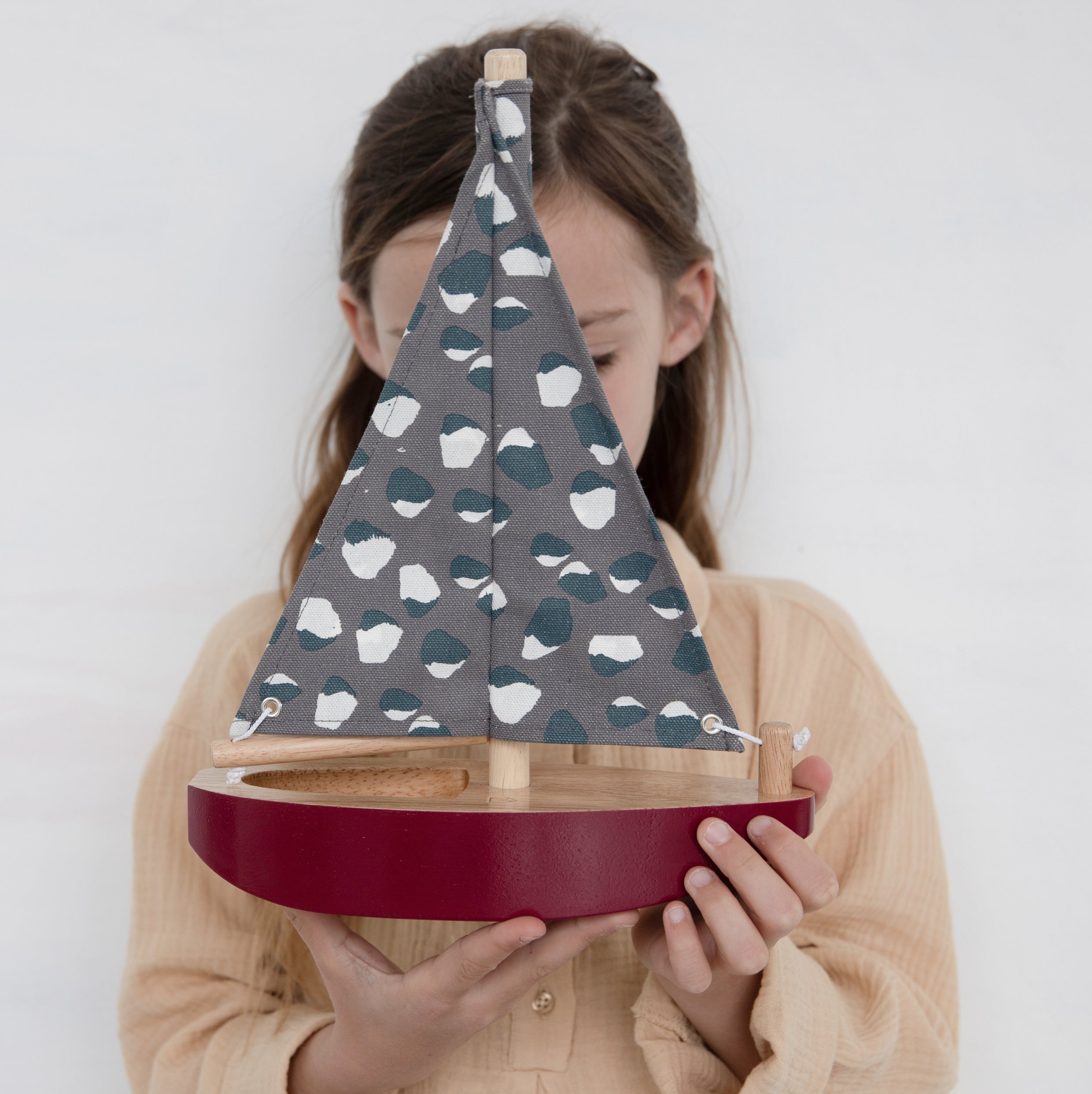 Girl holds Nofred Burgundy Toy Sailing Boat
