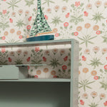 Shelving unit with a decorative item against a floral wallpapered wall