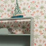 Shelving unit with a decorative item against a floral wallpapered wall