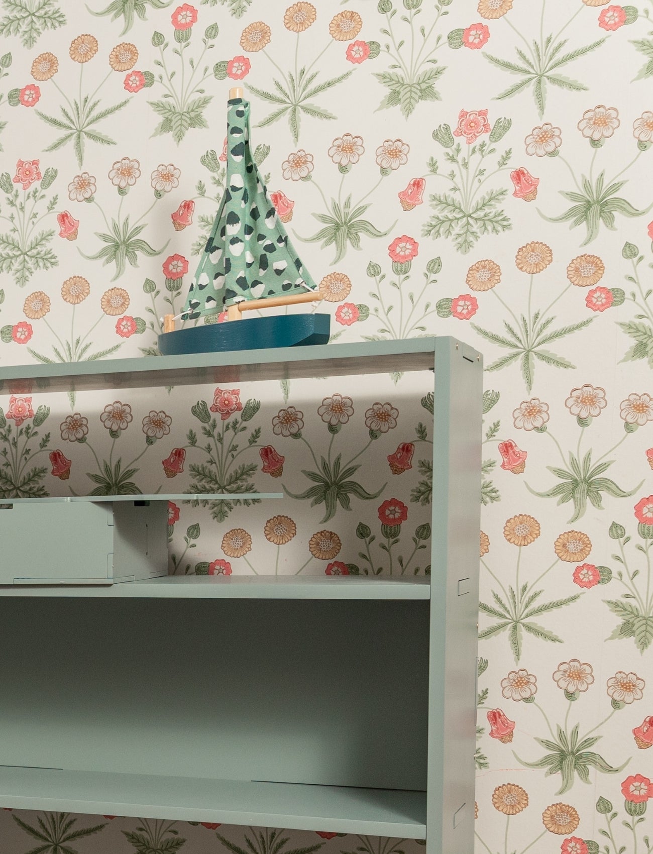 Shelving unit with a decorative item against a floral wallpapered wall