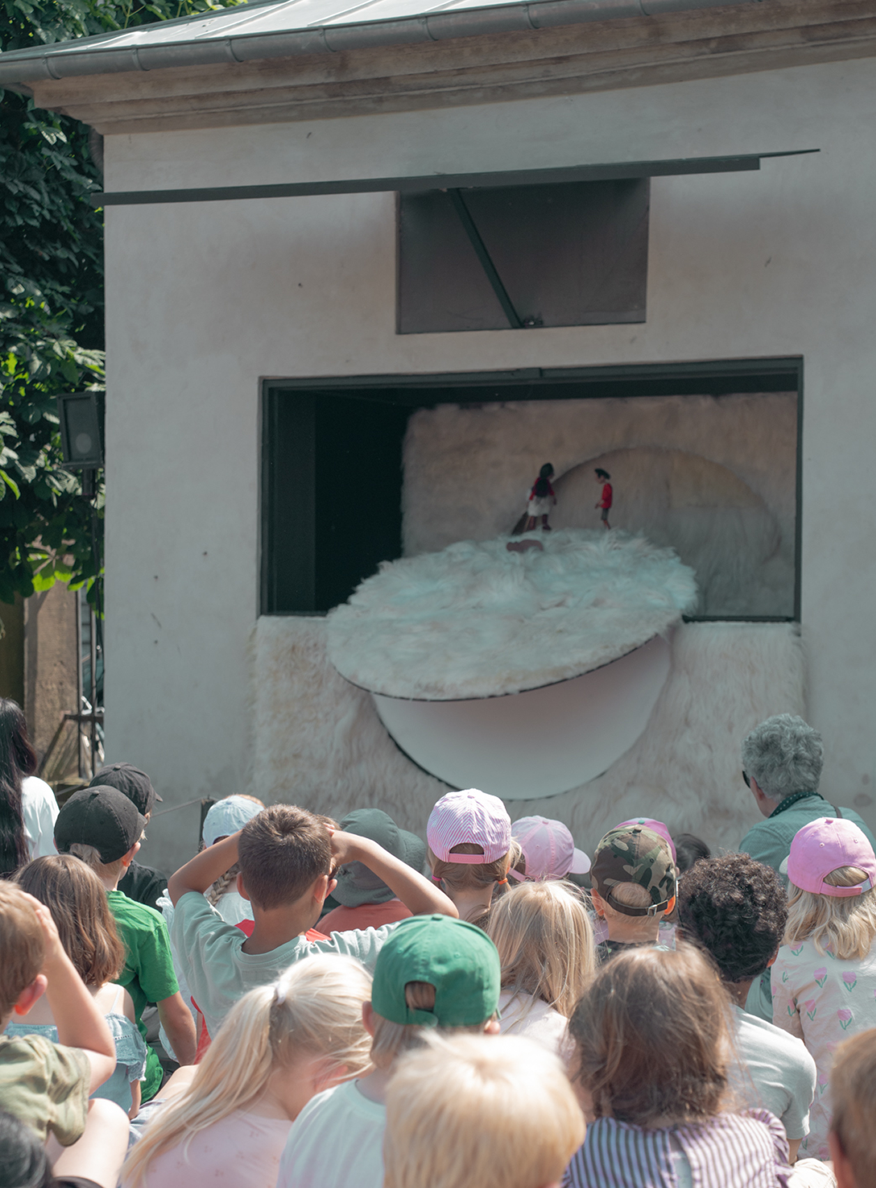 People watching a performance or art installation on a wall outdoors.