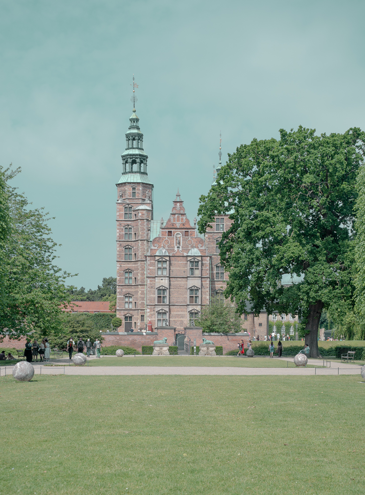 Historic brick building with a tall tower in a park setting