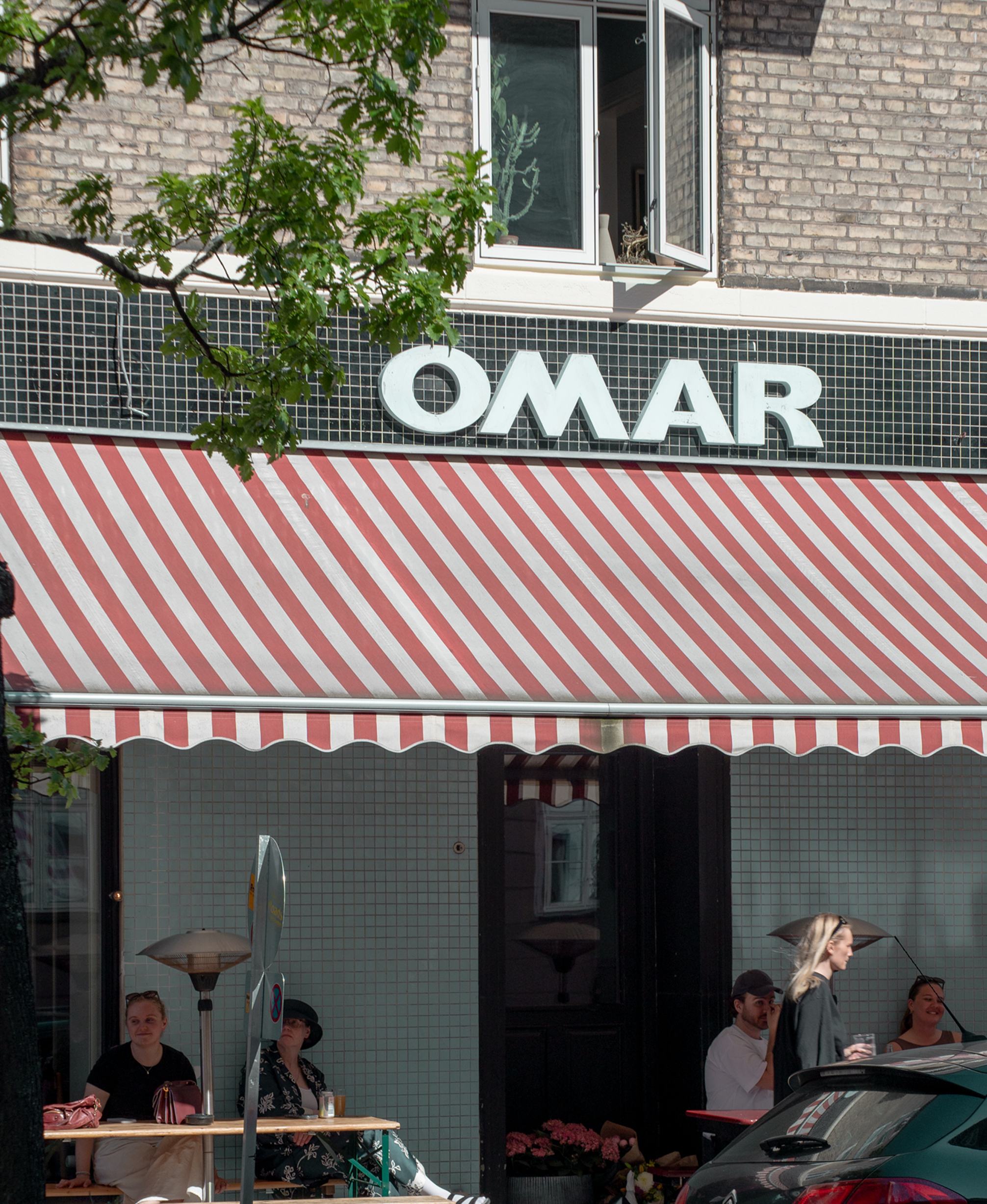 Restaurant 'Omar' with a red and white striped awning and people inside.