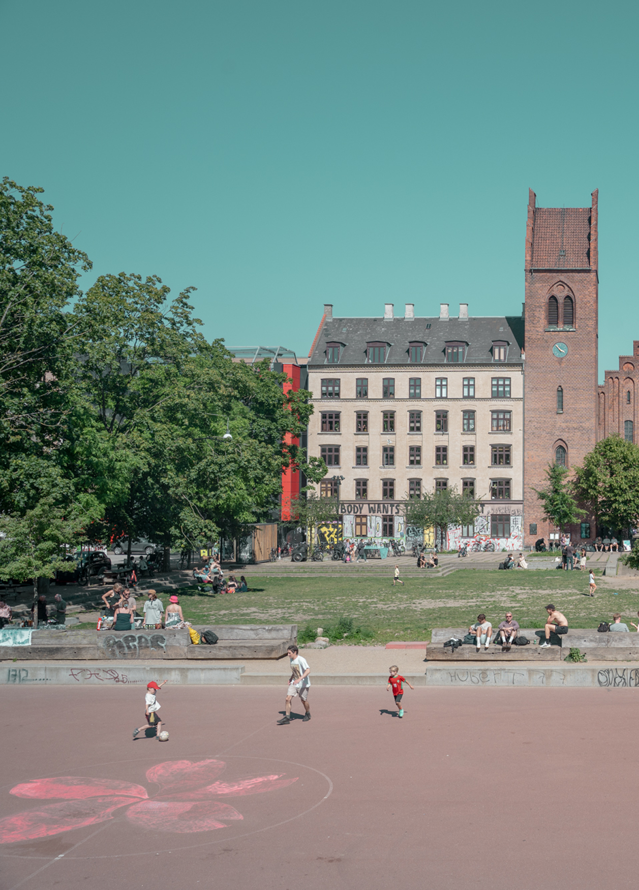 Children playing on a basketball court with a cityscape in the background
