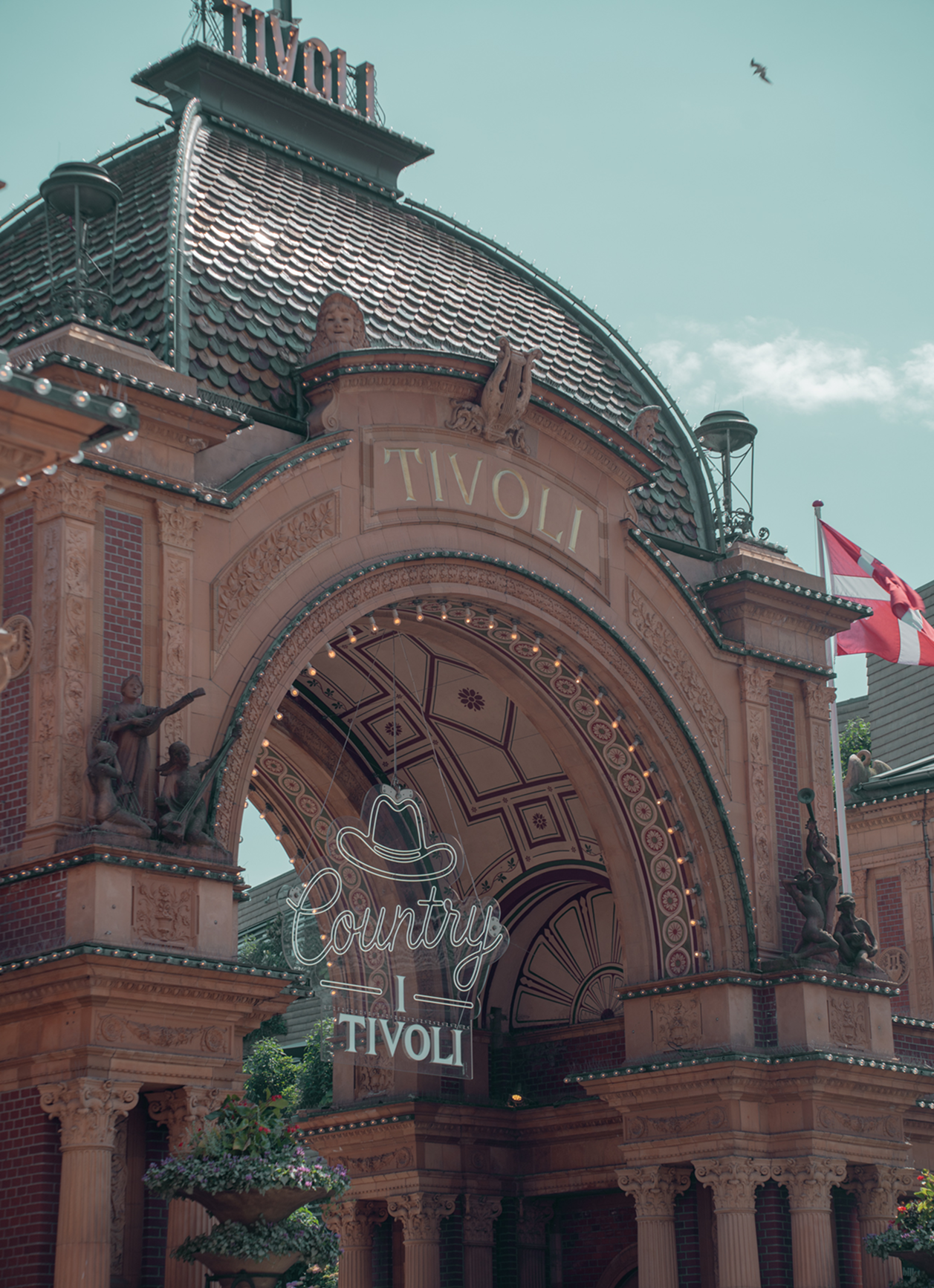 Decorative archway with 'Tivoli' branding and a sign for 'Country Tivoli' against a clear sky.