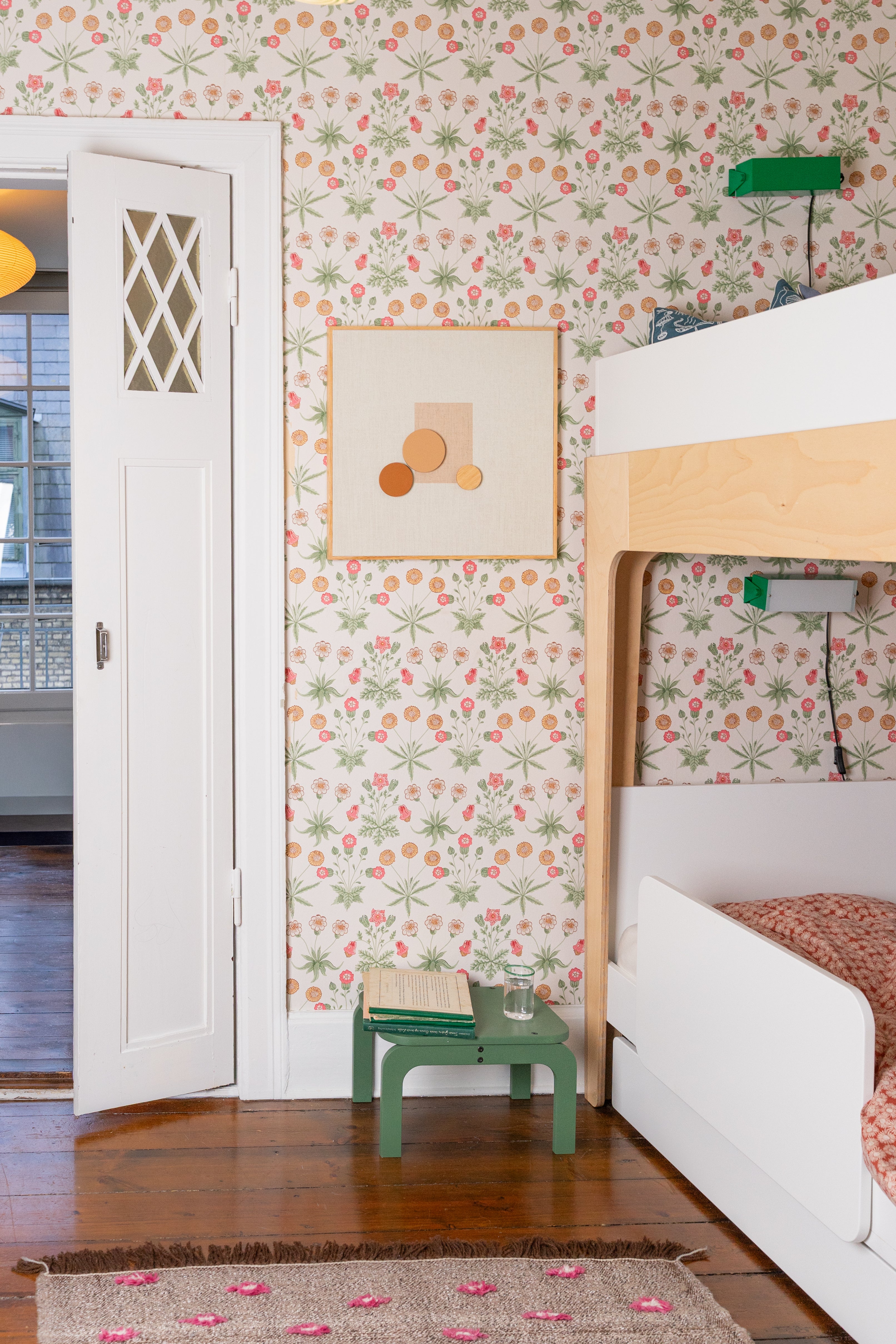 Children's room with floral wallpaper, bunk bed, and green stool.
