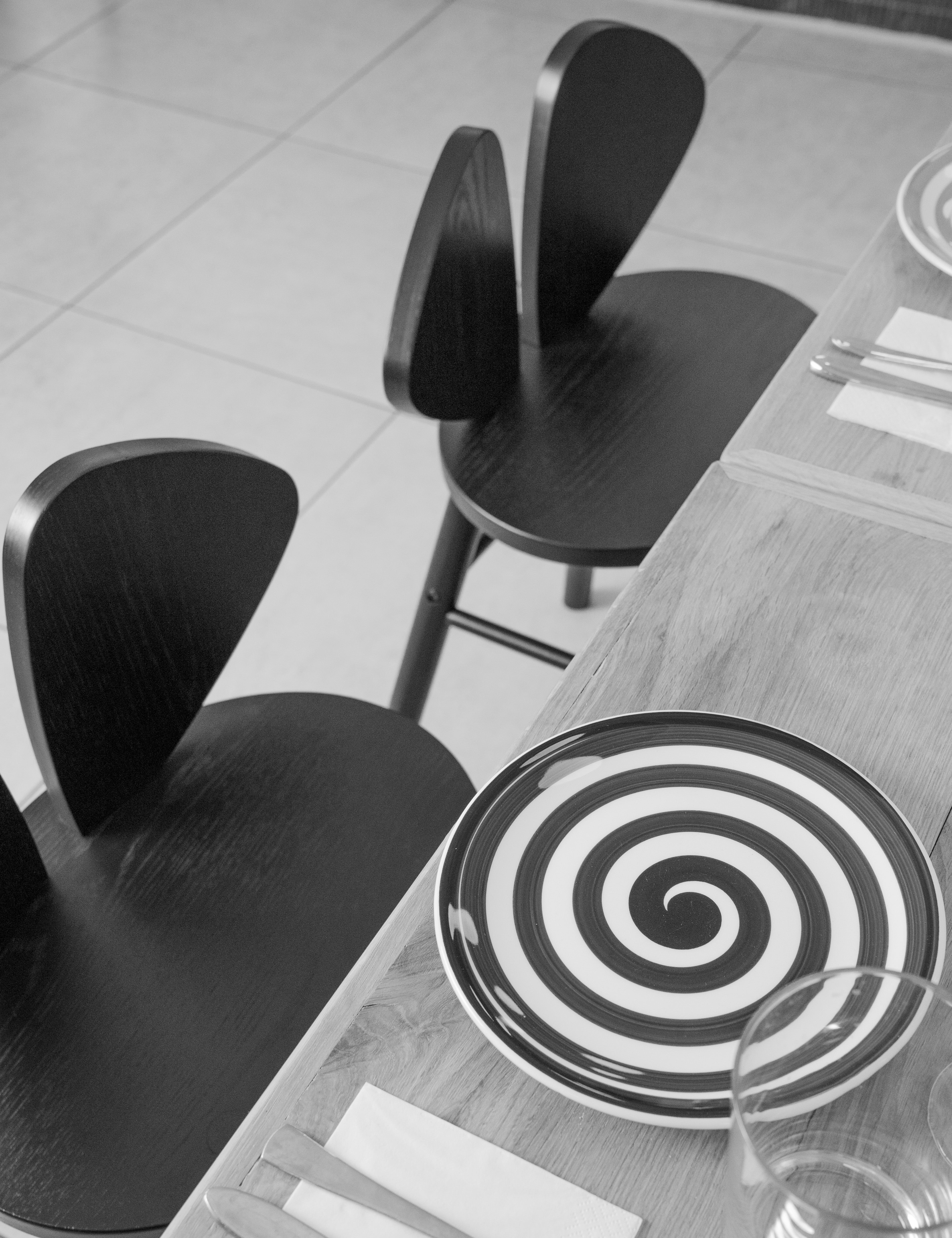 Black and white spiral plate on a table with two black chairs.