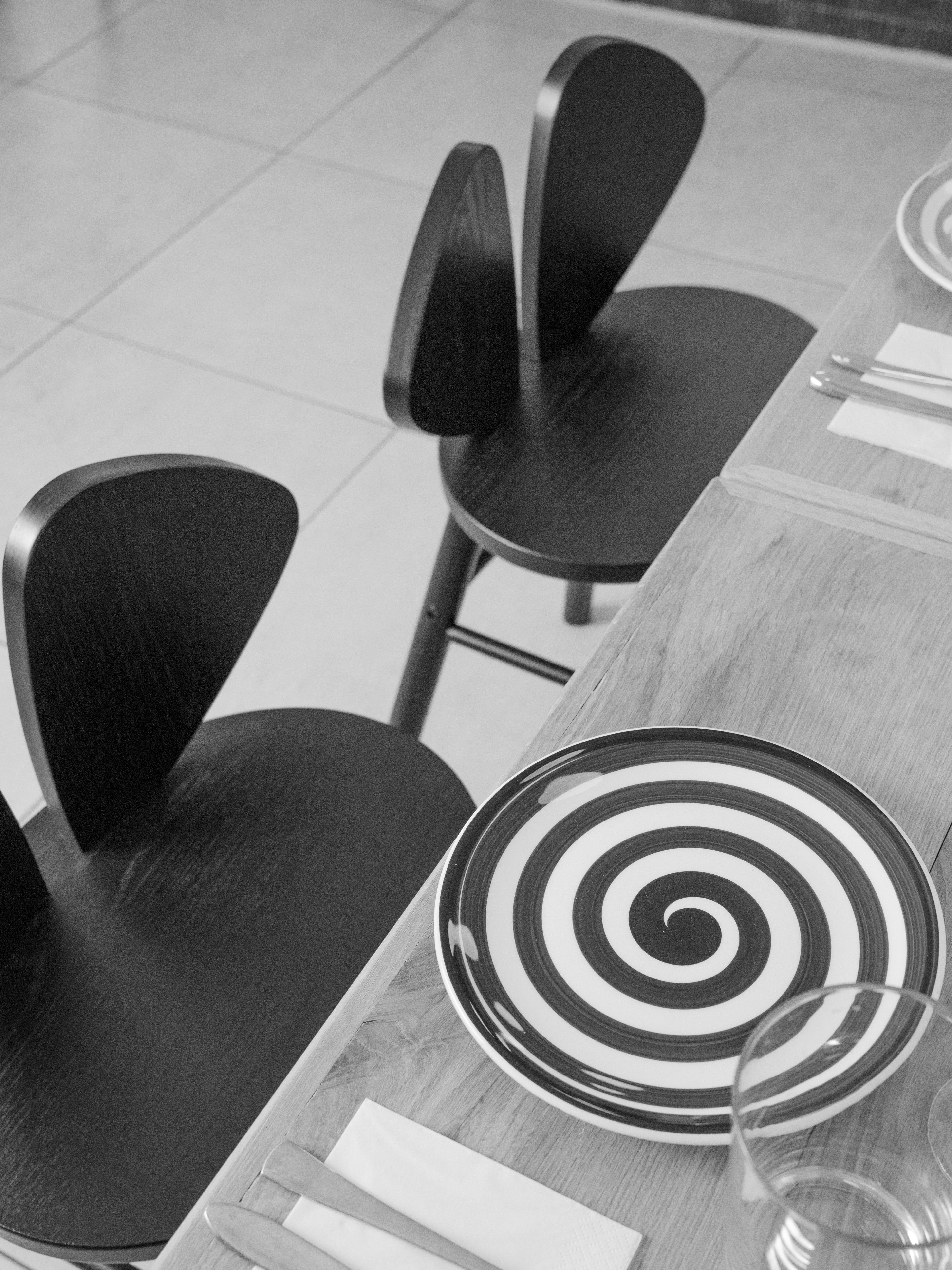 Black and white spiral plate on a table with two black chairs.