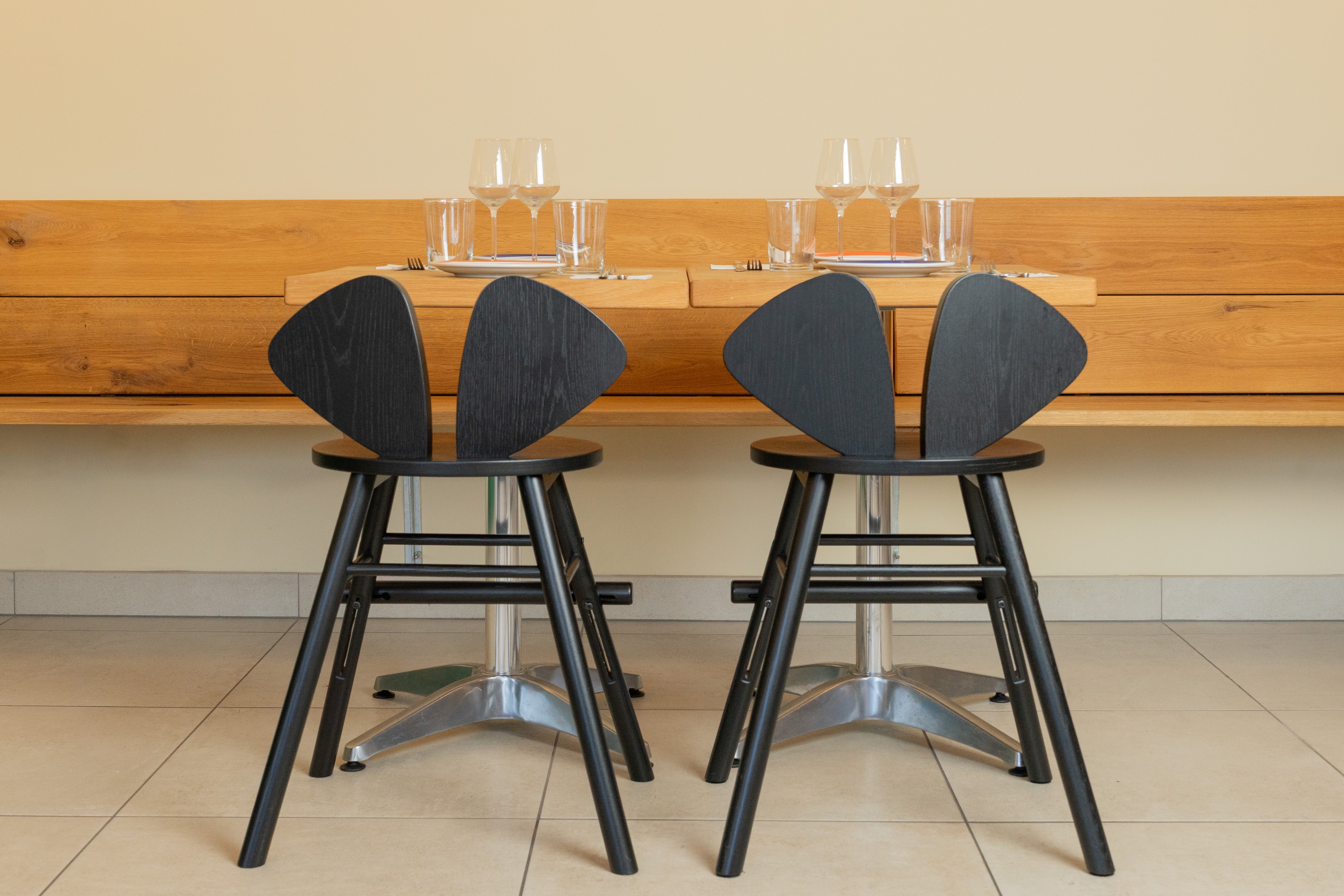 Two black stools with unique backrest designs in front of a wooden counter.