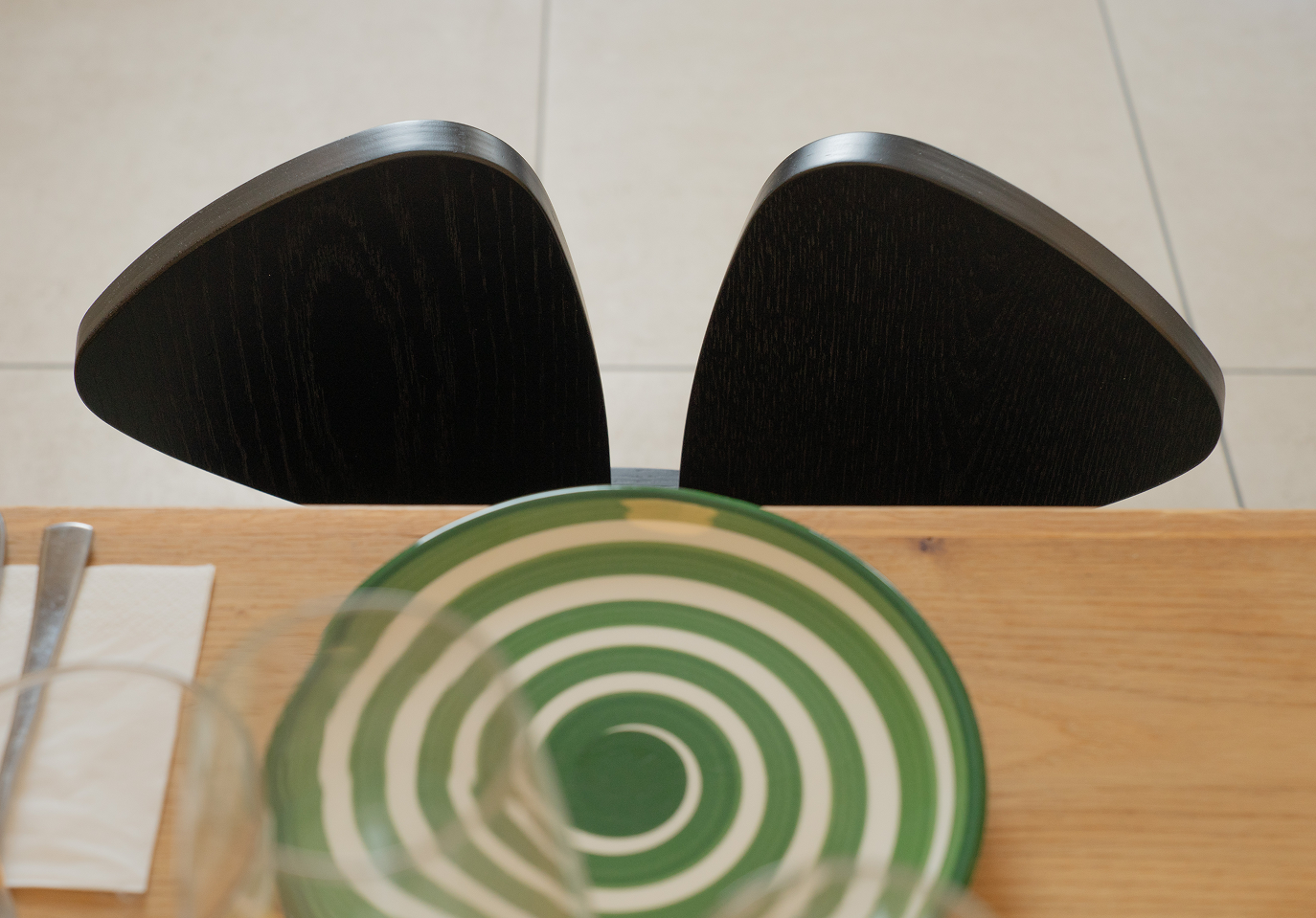 A black wooden chair at the table with a green and white plate in front of it