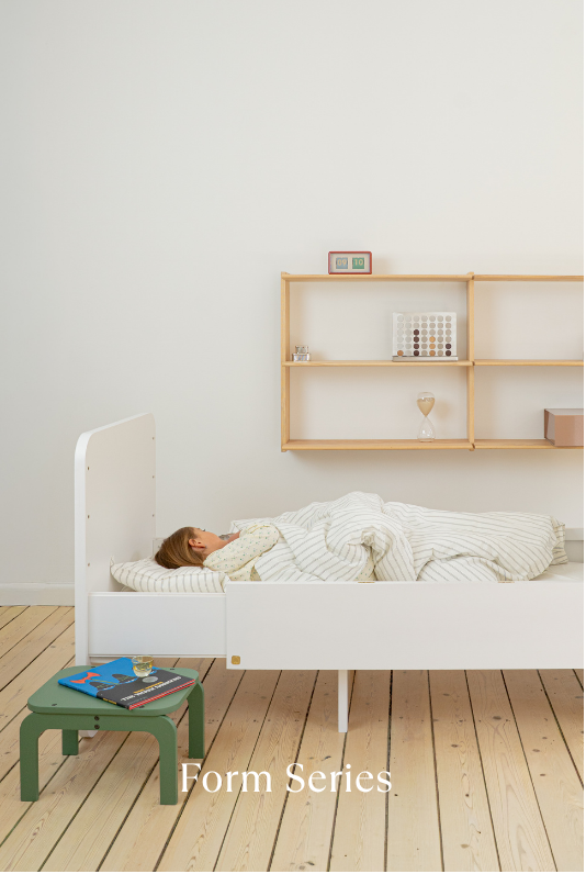 Child sleeping in a white bed with a wooden shelf in the background, labeled 'Form Series'.