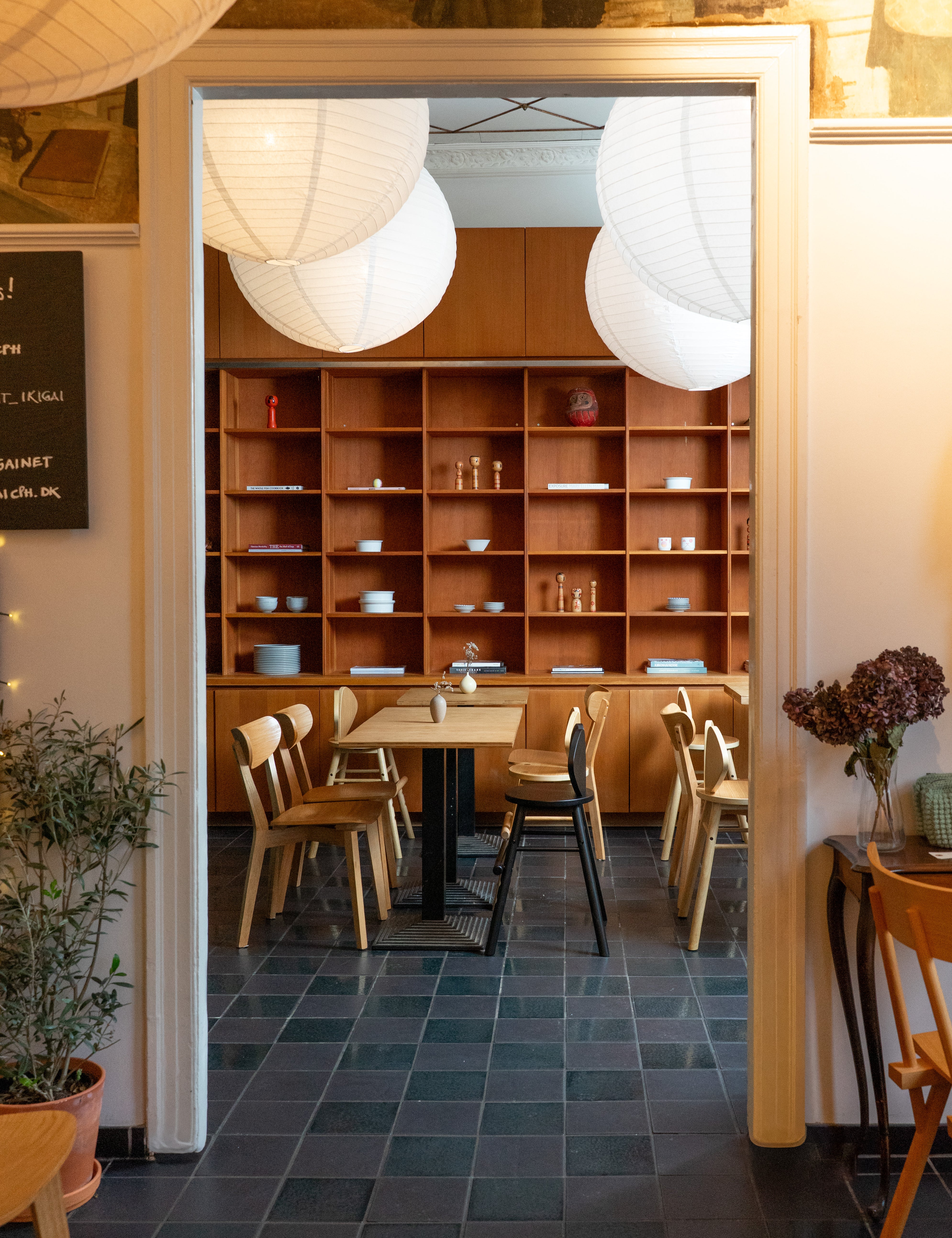 Restaurant interior with wooden shelves, tables, and chairs.