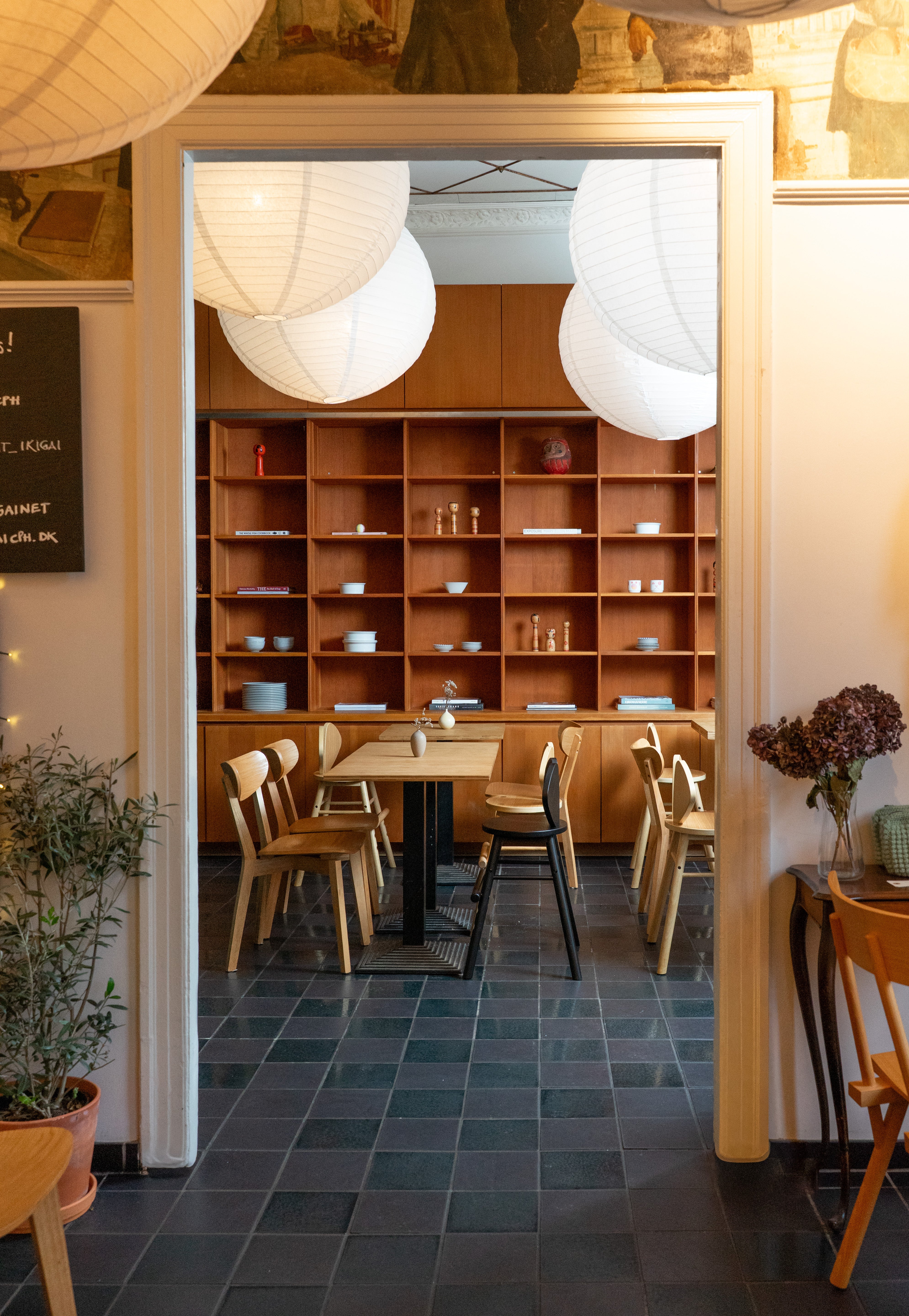 Restaurant interior with wooden shelves, tables, and chairs.