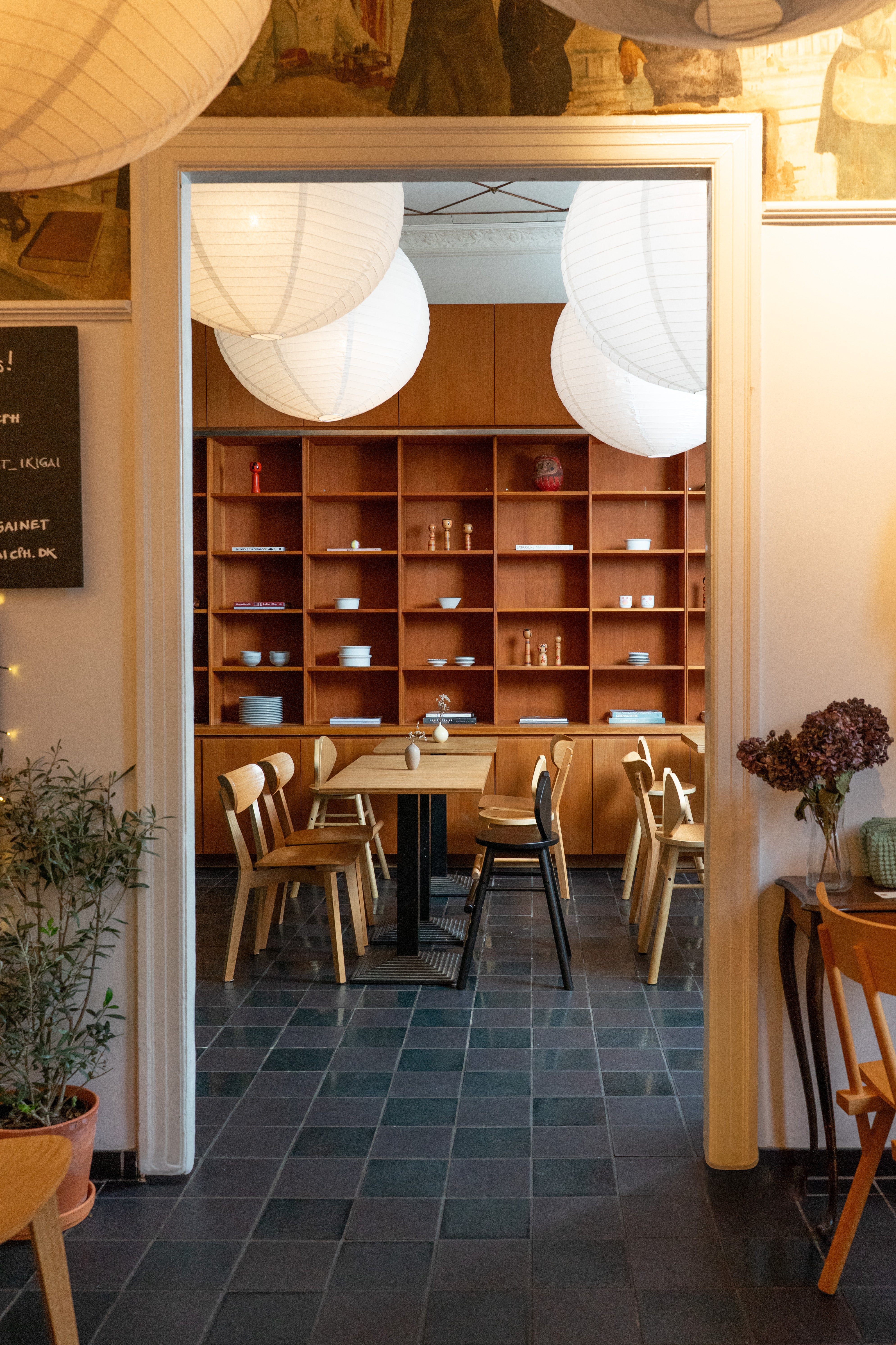 Restaurant interior with wooden shelves, tables, and chairs.