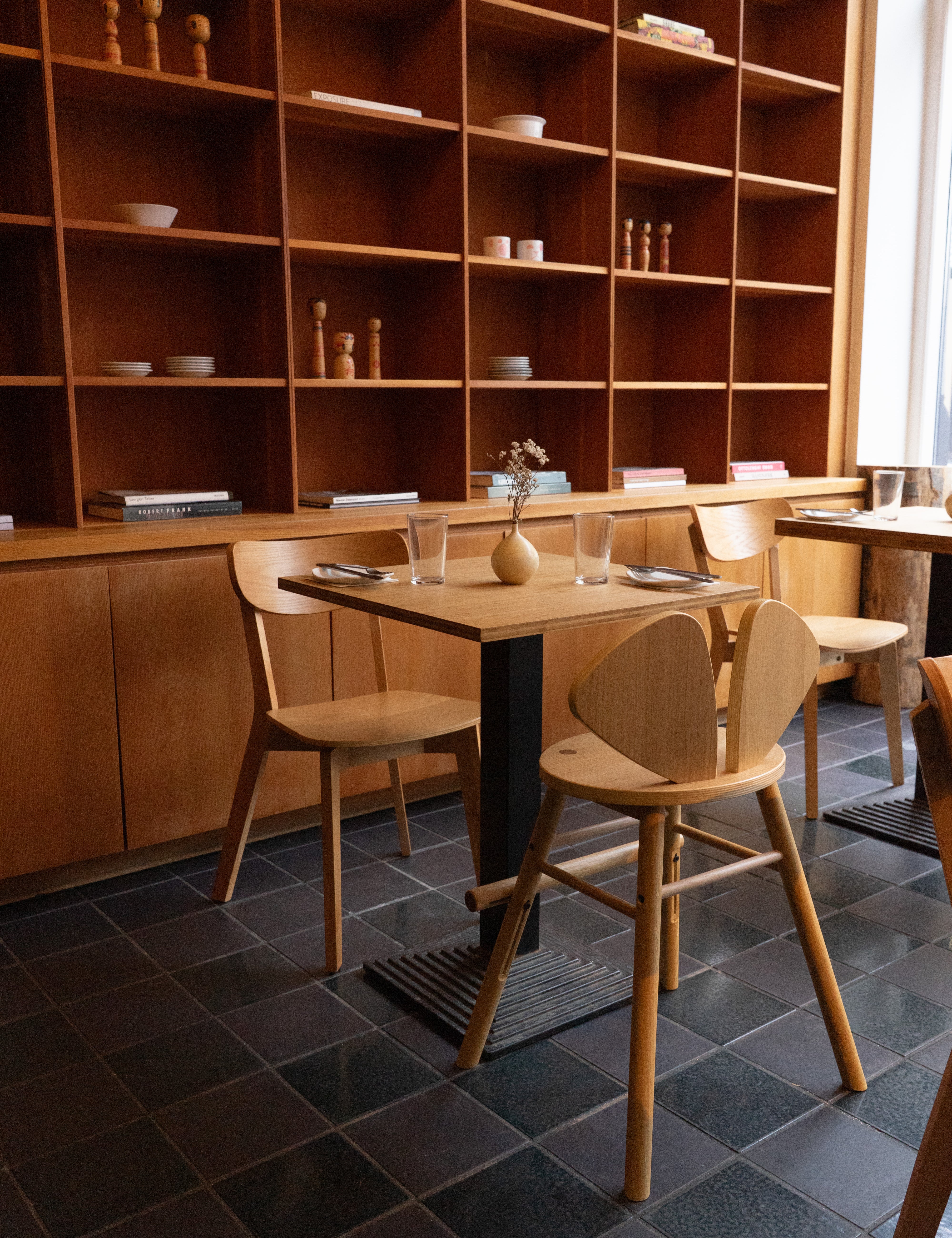 Dining area with wooden table and chairs in a room with wooden shelves.
