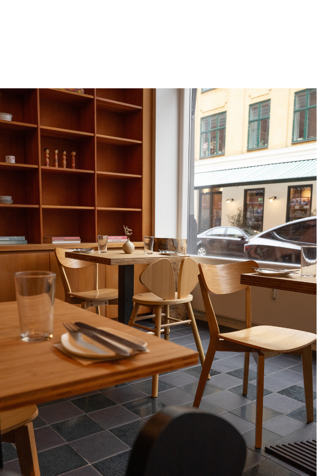 a restaurant interior with tables, chairs, and bookshelves.