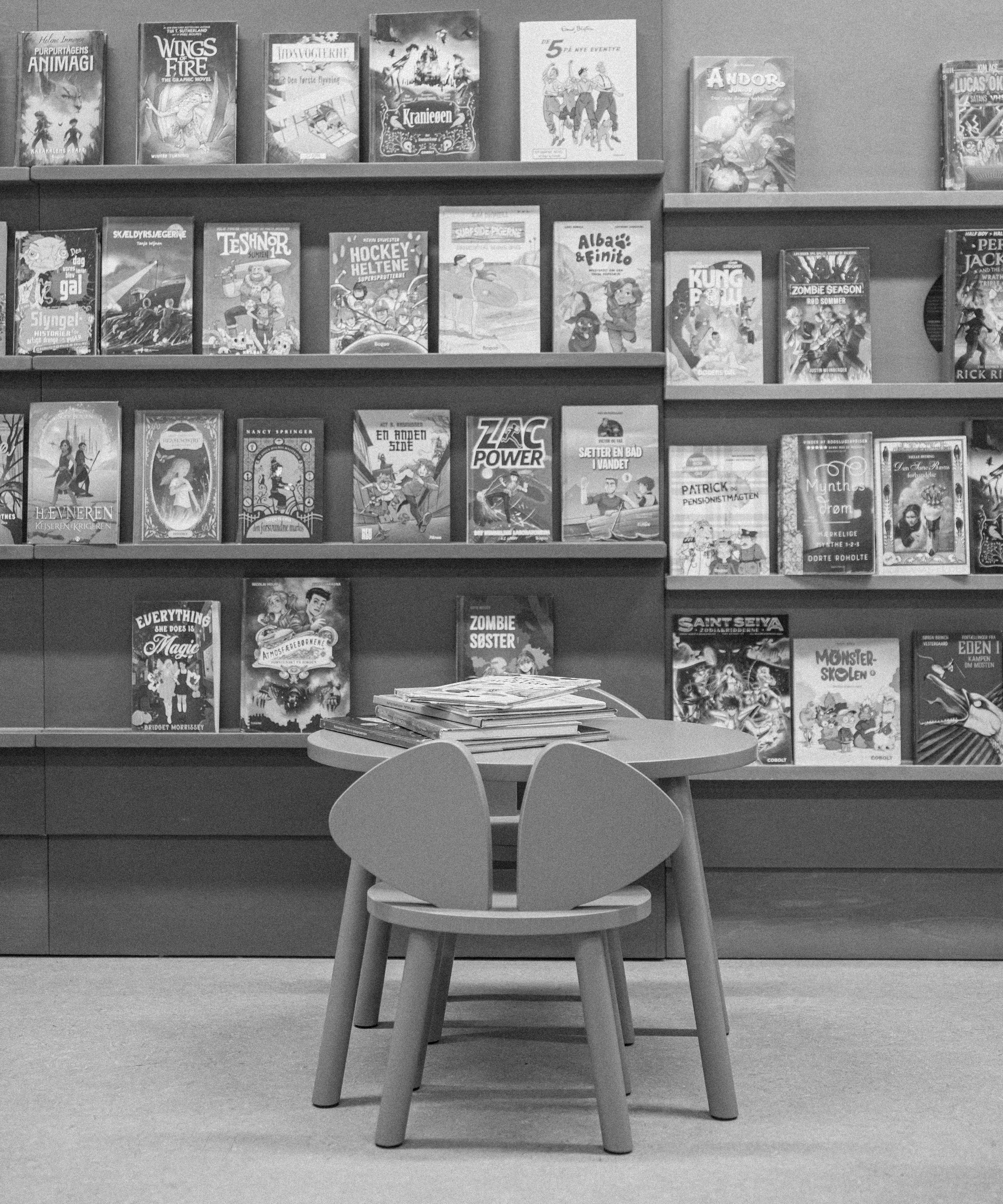 Children's bookshelves with various books and a small table with chairs in a room.