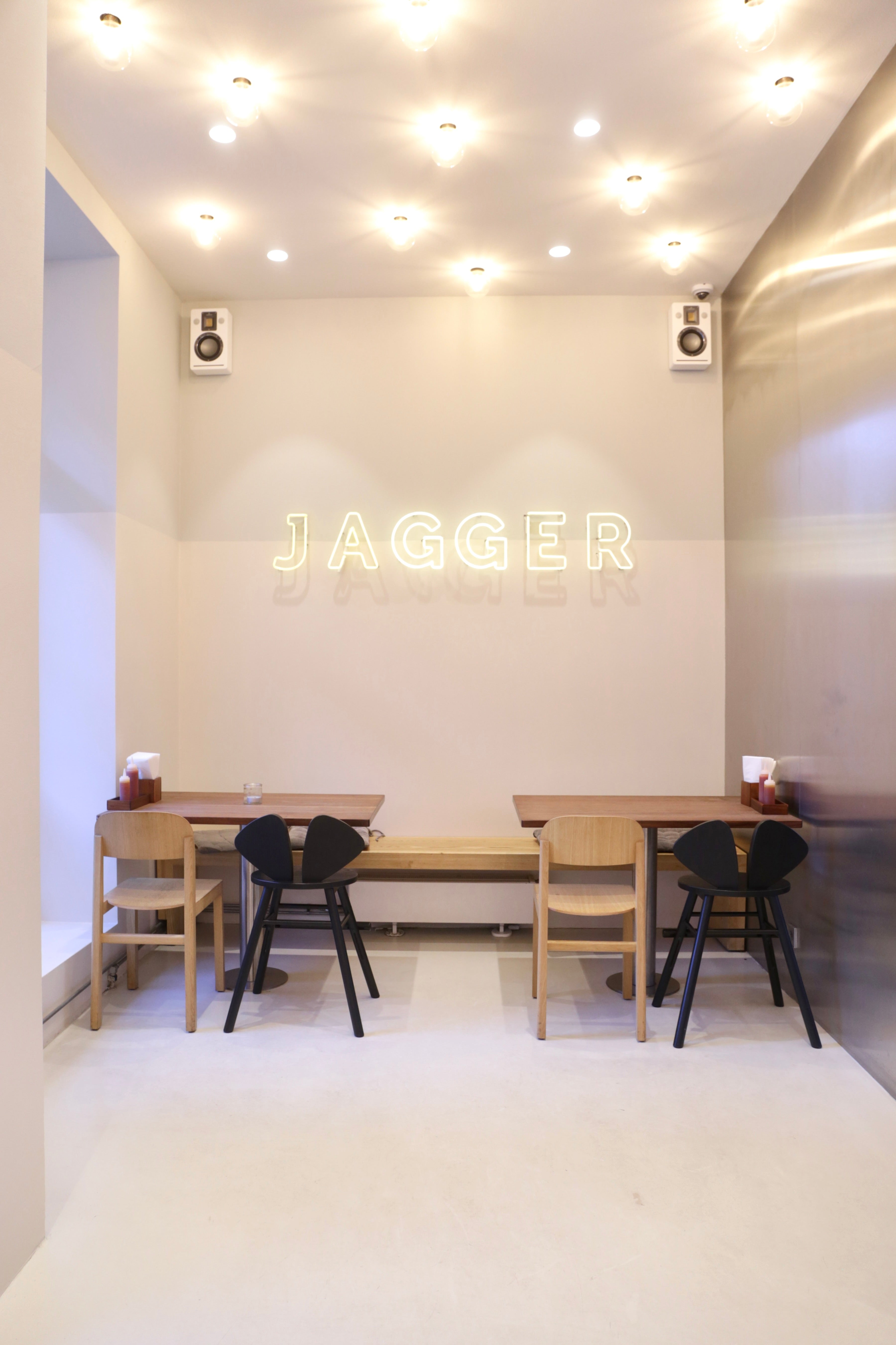 Modern interior with 'Jagger' neon sign above a dining area.