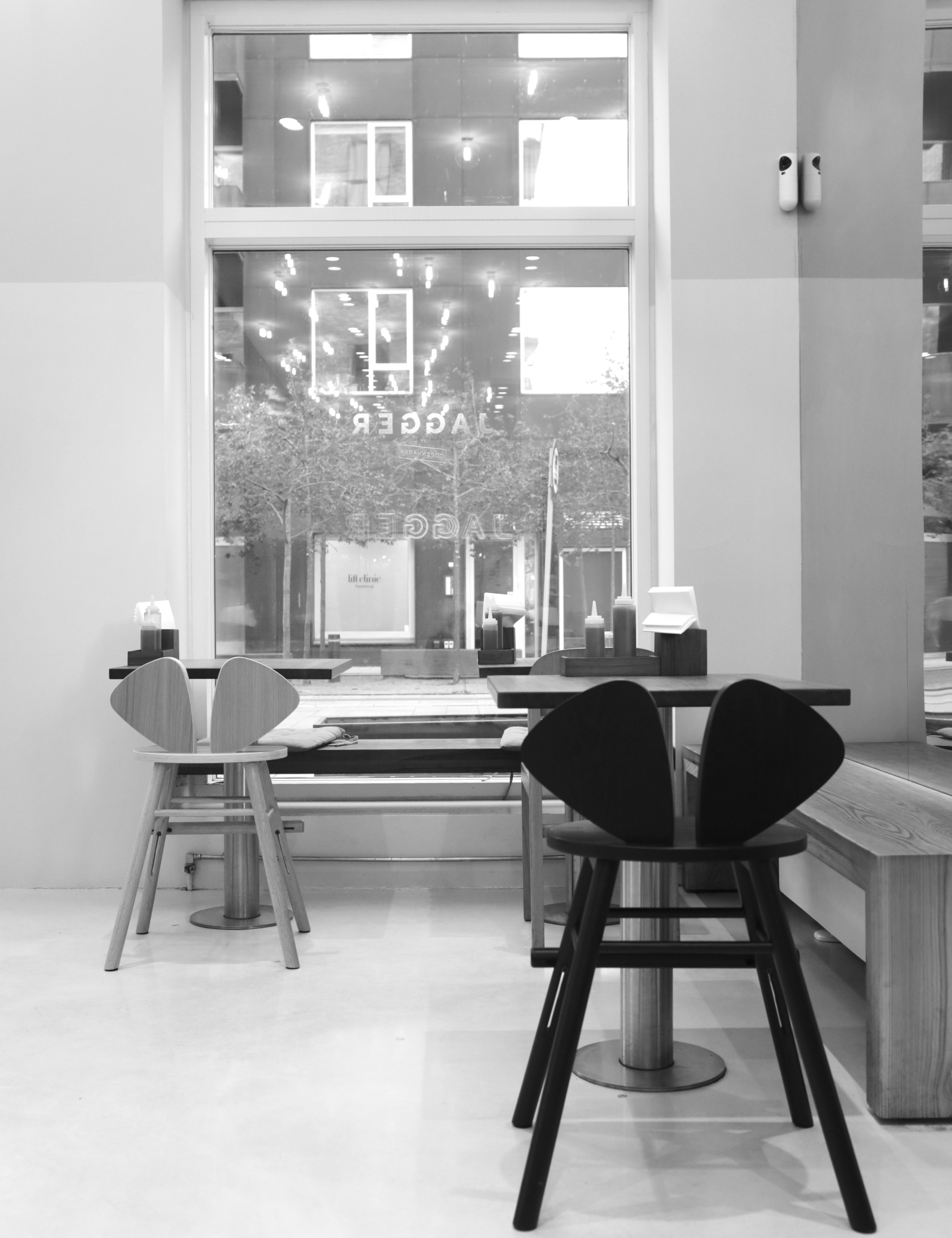 Modern interior with black chairs and a glass wall showing a store exterior.