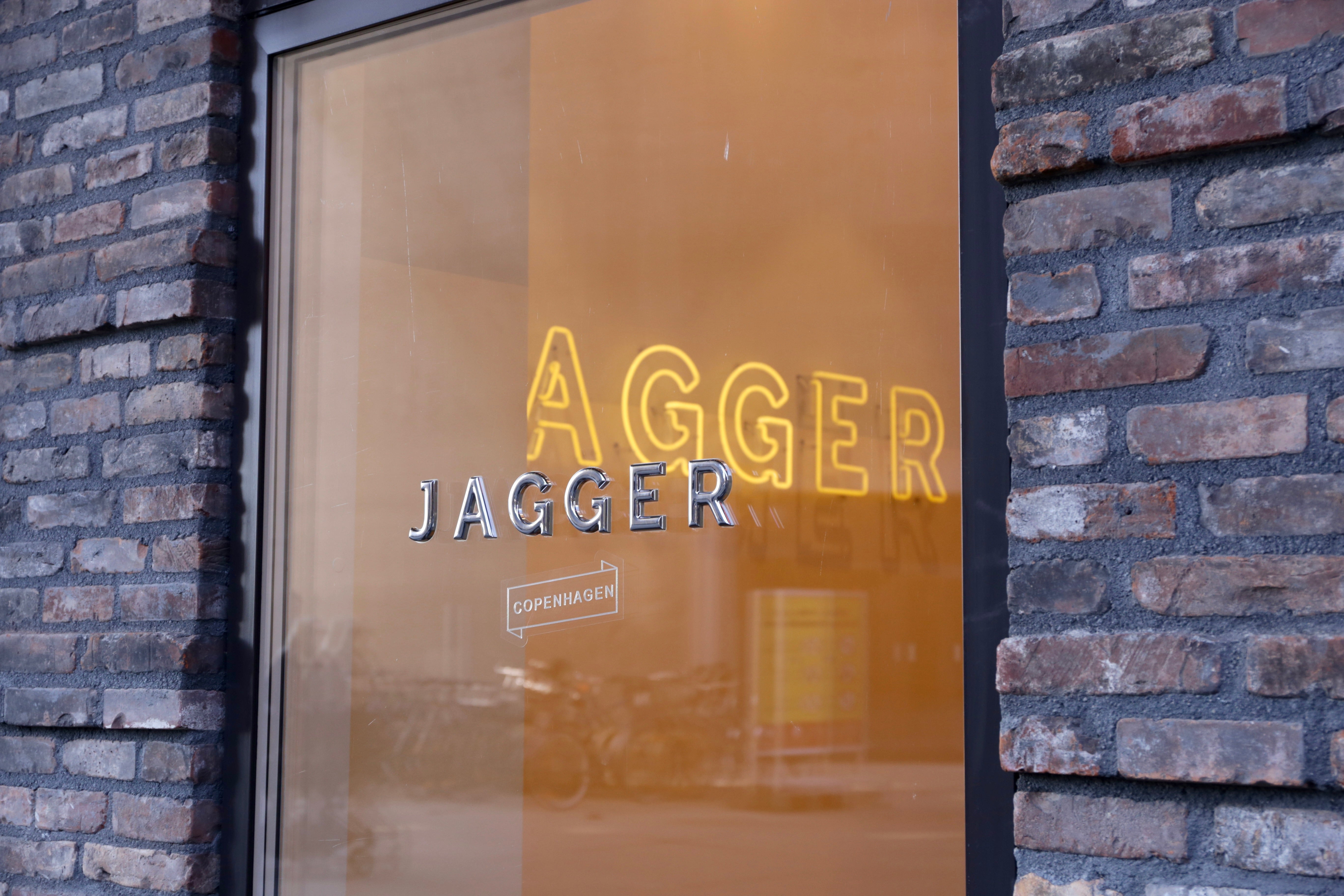 Glass door with 'Agger Jagger' branding on a brick wall.