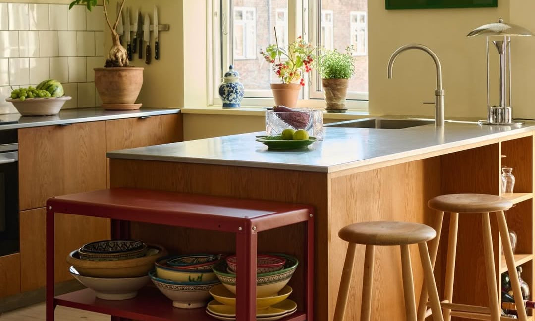 Modern kitchen with a red island shelf, stools, and a window view.